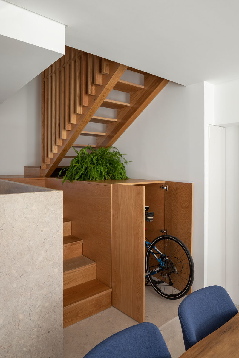 Storage Ideas - This small house includes a cabinet underneath the stairs that runs the depth of the stairs. The cabinet is large enough to hide a bike, and provides a place to display decorative items and plants. #HiddenStorage #UnderStairStorage #BikeStorage #InteriorDesign #StairDesign #StorageIdeas