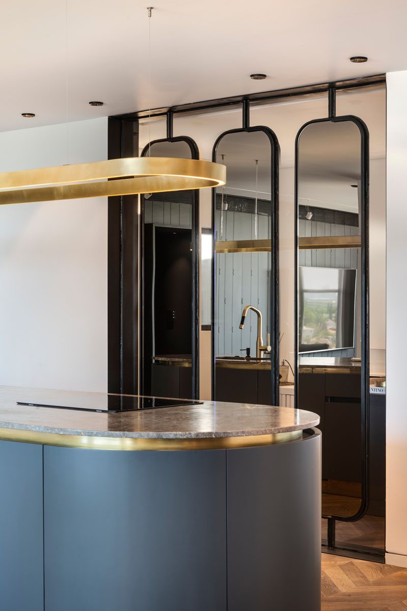 Separating the kitchen from the home office in this modern apartment, is a collection of three steel and mirror partitions. Each individual partition turns on an axis and can be adjusted to any chosen angle, while the mirrors reflect light throughout the interior. #PartitionIdeas #WallPartition #InteriorDesign #MirroredPartition