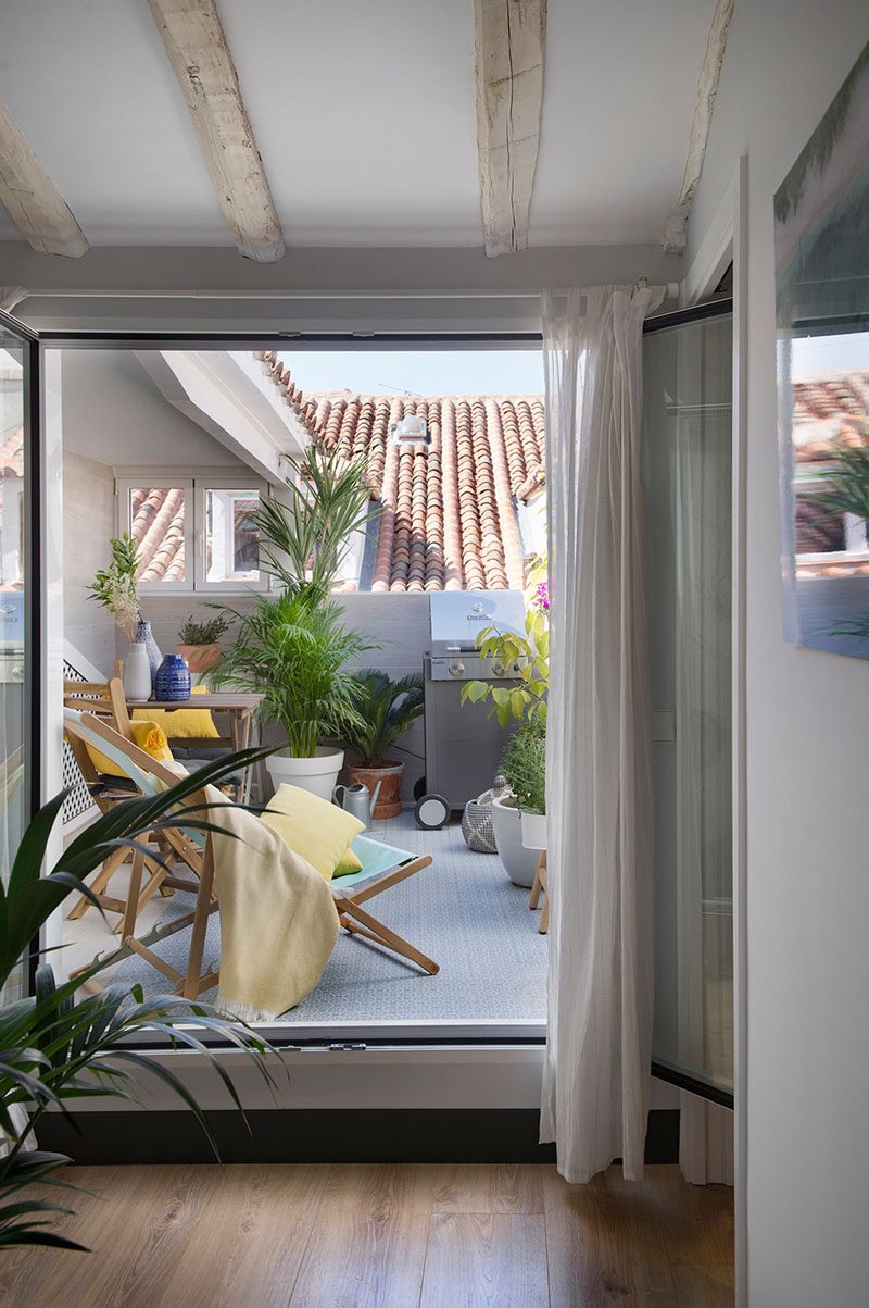 Just inside this contemporary apartment and by the front door, is a small terrace area that's furnished with some seating, a place to eat, and a bbq. #TerraceIdeas #BalconyIdeas #OutdoorSpace