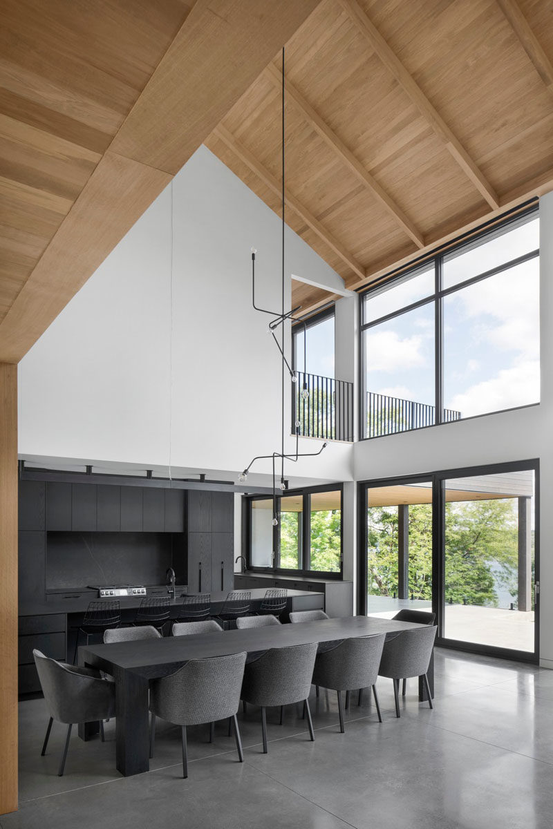 Modern Barnhouse Ideas - This modern barnhouse has a open-plan great room great room, where the grey furniture and dark kitchen complement the polished concrete floors, but at the same time contrast the bright interior. #ModernBarnhouse #ModernArchitecture #DarkKitchen #HighCeilings