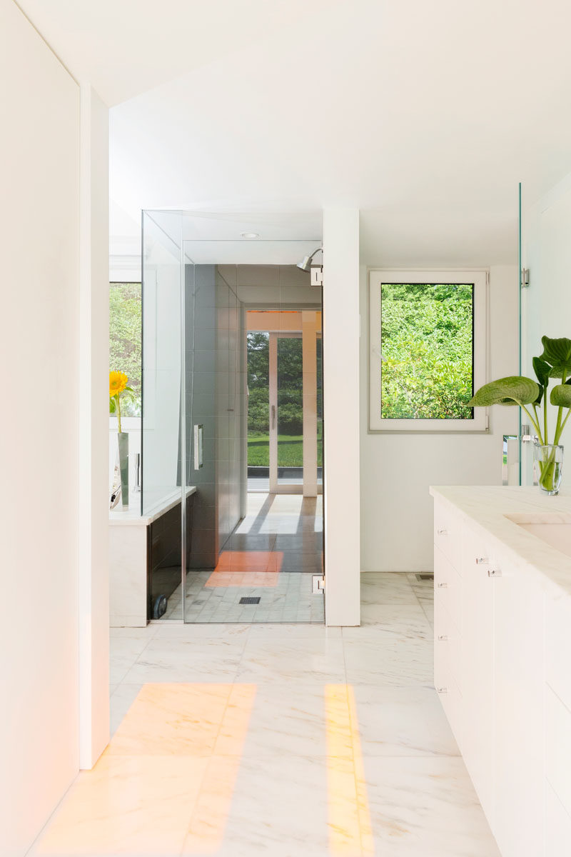 Bathroom Ideas - This modern en-suite bathroom features a walk-in shower, and a large vanity with plenty of storage. A glimpse of the colors from the hallway shine through to the bathroom. #BathroomIdeas #ModernBathroom #BathroomDesign