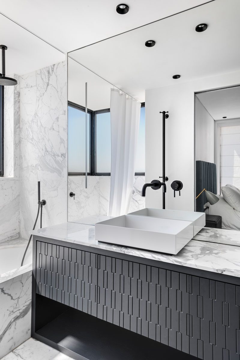 In this modern bathroom, grey stone walls and countertops are contrasted by black accents and a black vanity. #ModernBathroom #BlackAndGreyBathroom #BathroomIdeas