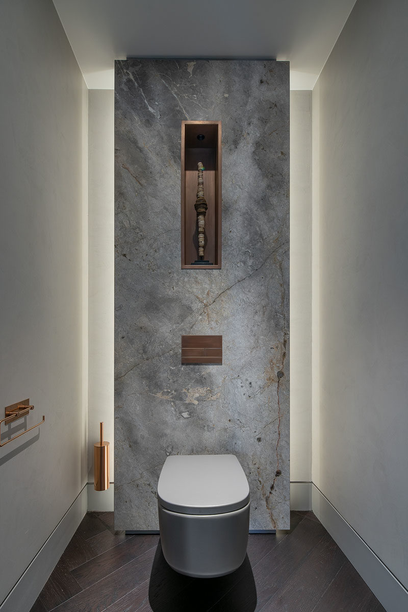 Bathroom Ideas - In this modern bathroom, a stone accent wall is highlight from behind, while a built-in shelf allows a small sculpture to be showcased. #BathroomIdeas #ModernBathroom #BathroomDesign