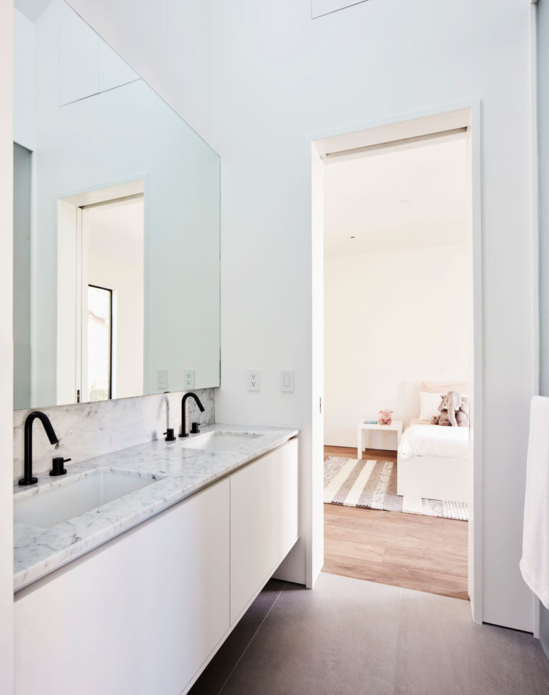This modern bathroom has minimalist cabinets, dual sinks, and black accents. #ModernBathroom #BathroomDesign #BathroomVanity