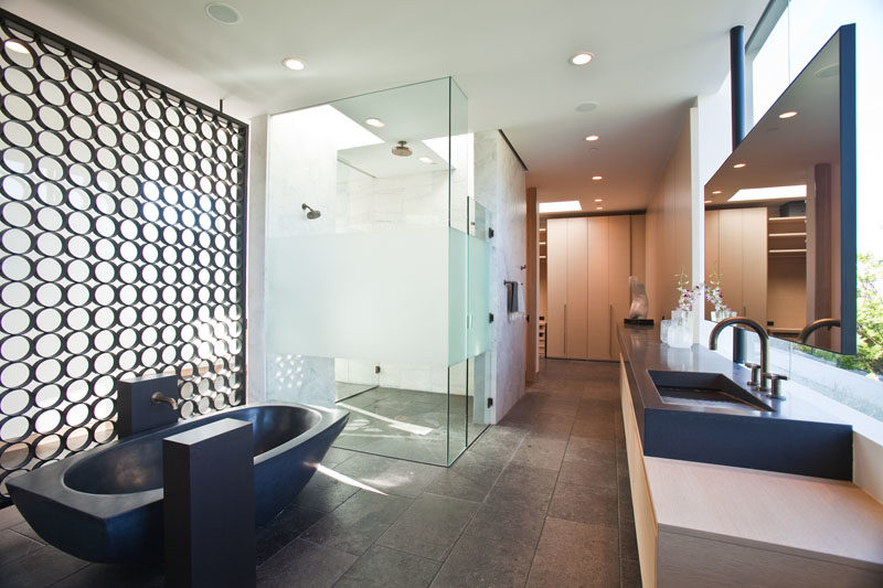 Bathroom Ideas - This modern master bathroom features a glass enclosed shower that receives natural light from the skylights above, while a black freestanding bathtub matches the vanity countertop with integrated sinks. #MasterBathroom #BathroomIdeas #FreestandingBathtub #BathroomVanityIdeas