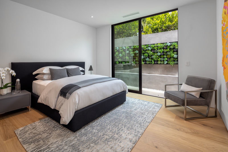 A modern guest bedroom with a sliding glass door that opens to a small outdoor space with a succulent wall.