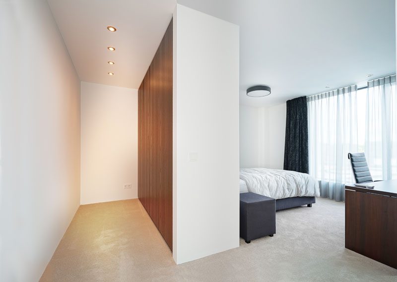 In this bedroom, there's floor-to-ceiling windows, and partial wall that provides a backdrop for the bed, and acts as a wardrobe on the other side. #BedroomDesign #ModernBedroom