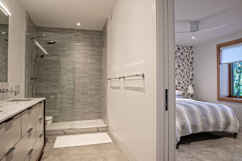 Bathroom Ideas - A pocket door opens to reveal the en-suite bathroom, where there's a walk-in shower and a vanity with double sinks. #BathroomIdeas #ModernBathroom