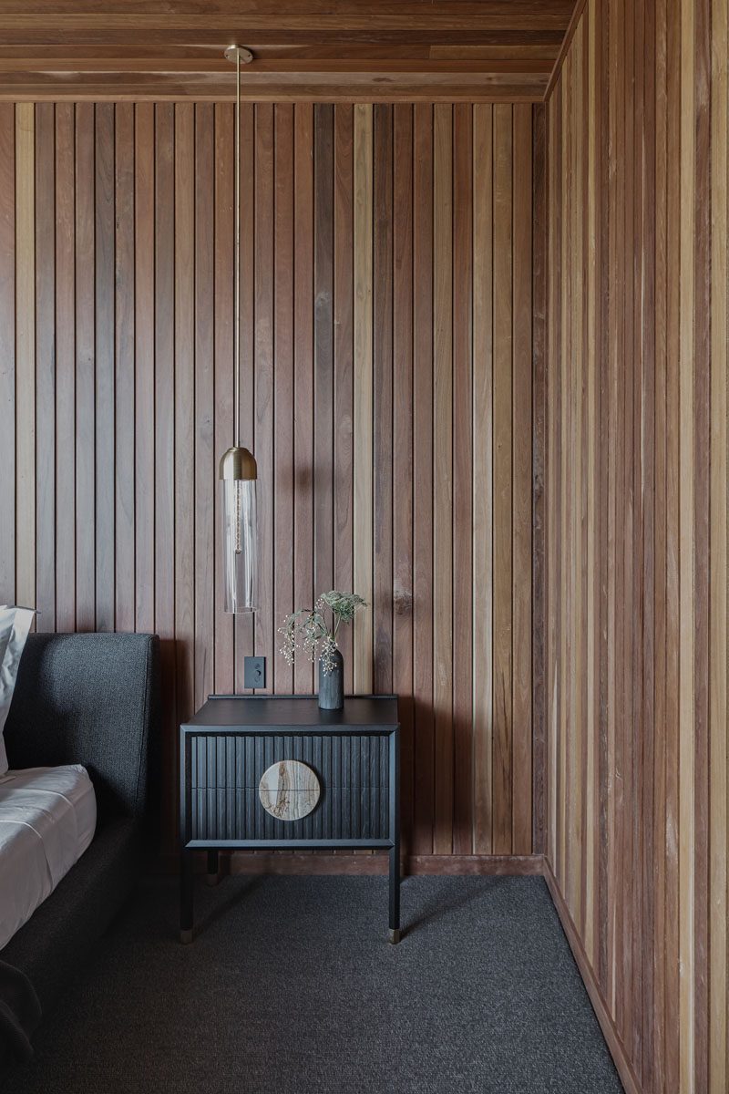 Thin lengths of wood in different shades have been used on the walls and ceiling, creating a natural warmth for this modern bedroom. #BedroomDesign #WoodWalls #WoodCeiling #ModernBedroom