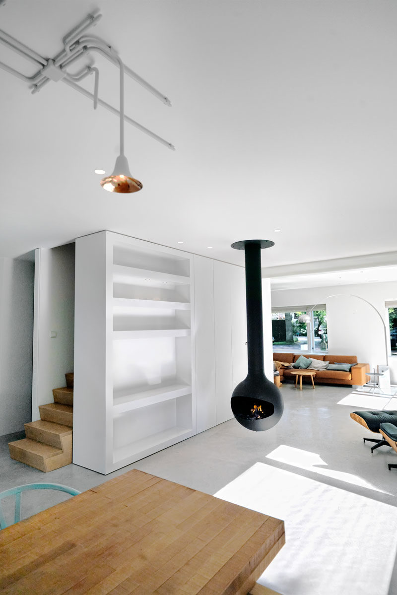 Interior Design Ideas - Concrete floors have been added throughout this new house addtiion, while a hanging black fireplace provides contrast to the bright white interior, and a new staircase acts as the backbone of the house, connecting the first floor and attic to the ground level and garden. #HangingFireplace #WhiteInterior