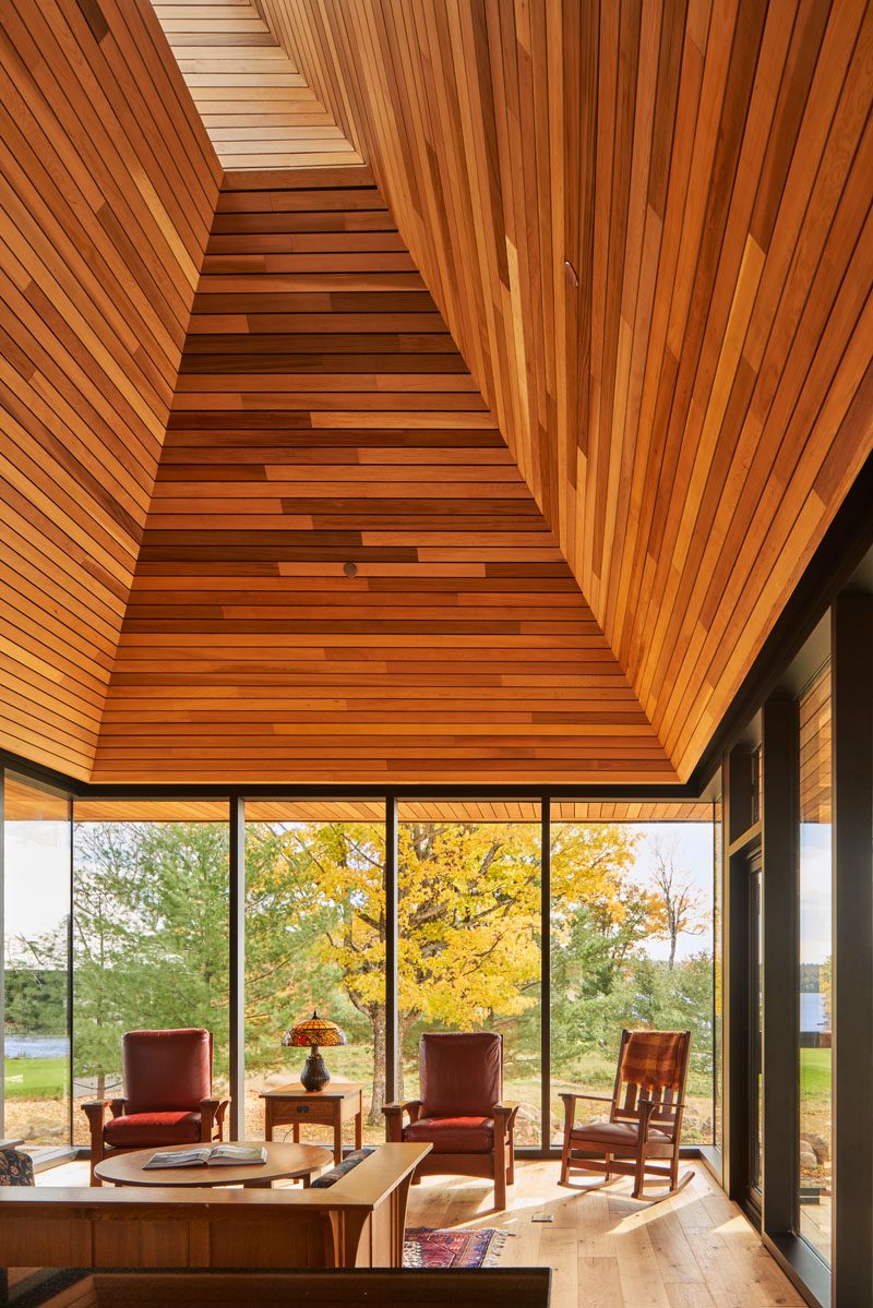 This modern cabin has an open living room and kitchen that are naturally lit from above via a periscope window in the gable. #ModernCabin #WoodCeiling #PeriscopeWindow #LivingRoom #CabinInterior