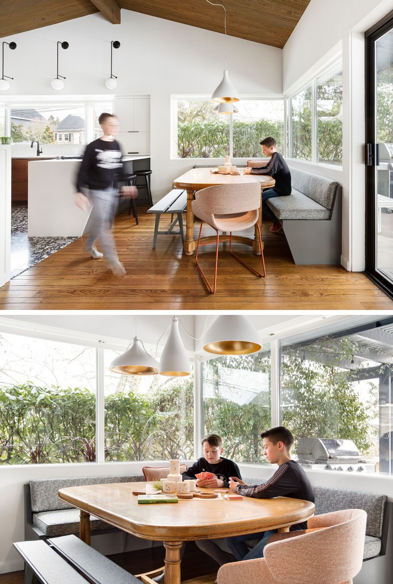 This modern dining area has banquette seating that lines the corner, and multiple white pendant lights that highlight the table. #DiningRoom #DiningNook #BanquetteSeating