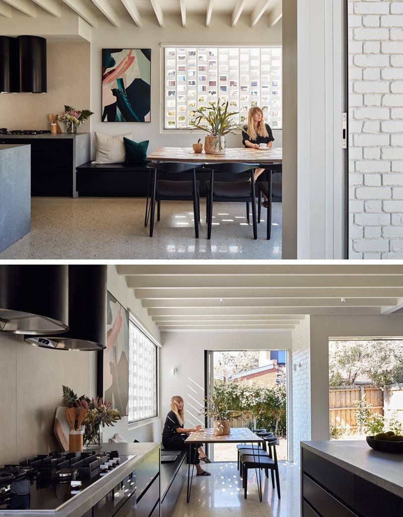 This open plan dining area has a wood table that's surrounded by black dining chairs on one side, and a long black banquette bench on the other. #DiningRoomIdeas #ModernDiningRoom #BanquetteBench #BenchSeating