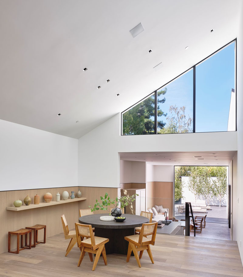 The social areas of this modern house are split between the living room and dining area, with the kitchen located on a lower level. #ModernHouse #DiningRoom #Windows