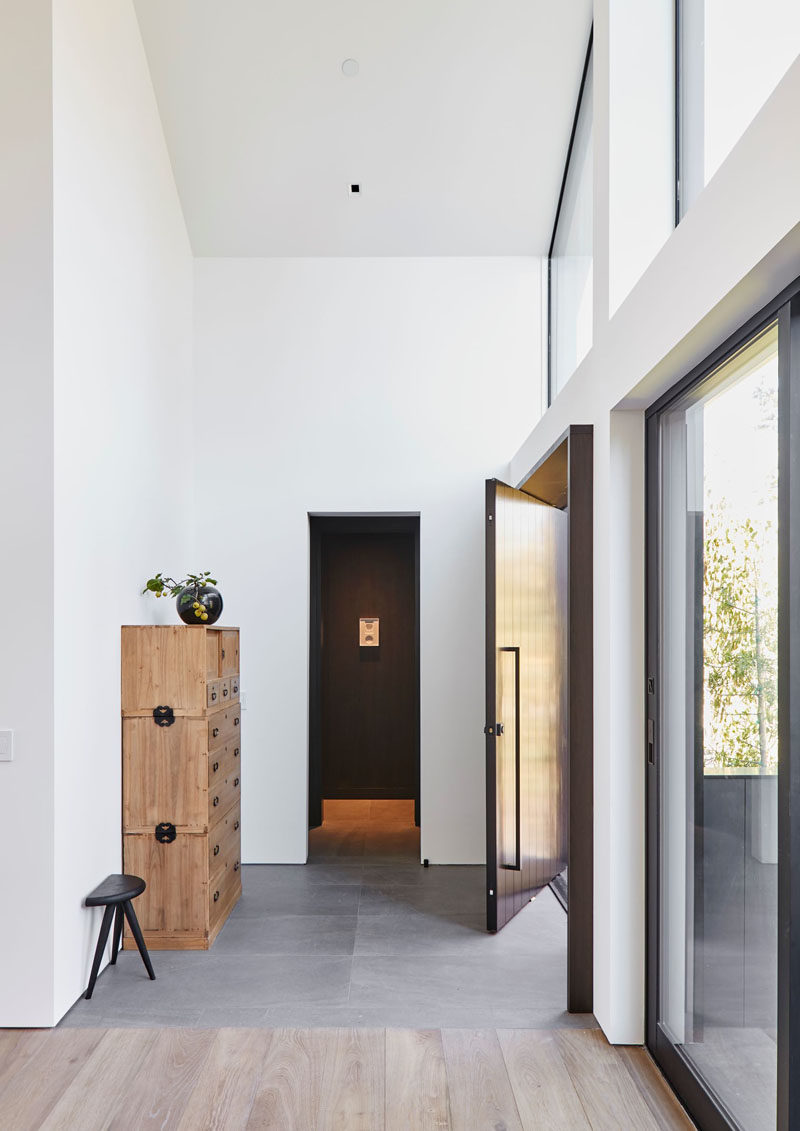 Inside the pivoting front door of this modern house, is a foyer with high ceilings and grey tiles. #ModernHouse #ModernInterior #Foyer