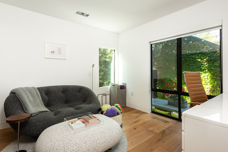 This modern home office overlooks the outdoor dining area, and is furnished with a comfortable couch and work area. #HomeOffice #Den #ModernHomeOffice