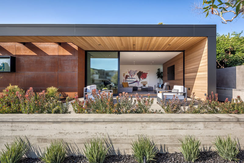 Large sliding glass doors open the living room of this modern house, to a covered front patio that looks out onto the street. 