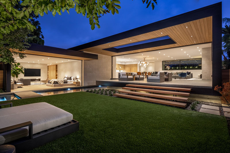 The partially covered patio of this modern house steps down to the yard, where there's a daybed, and a pool with a spa. 