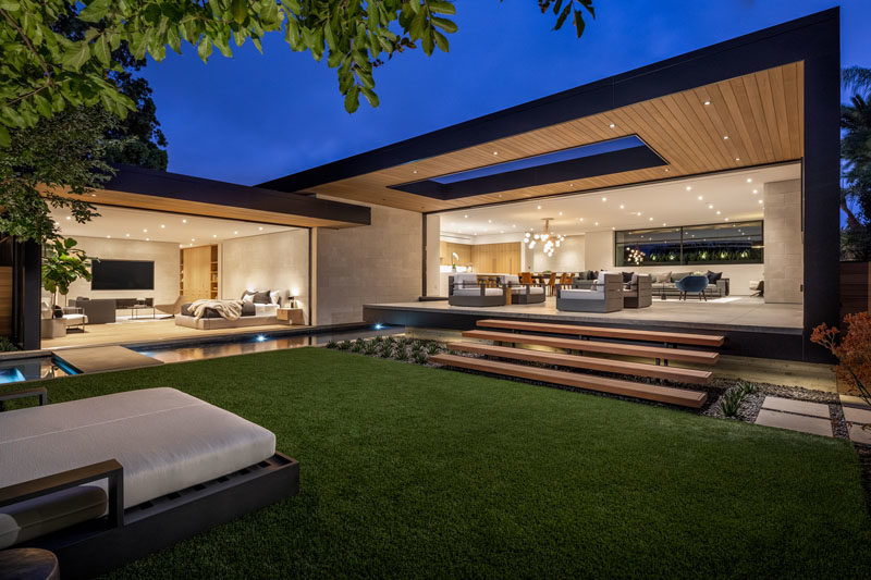 The partially covered patio of this modern house steps down to the yard, where there's a daybed, and a pool with a spa.