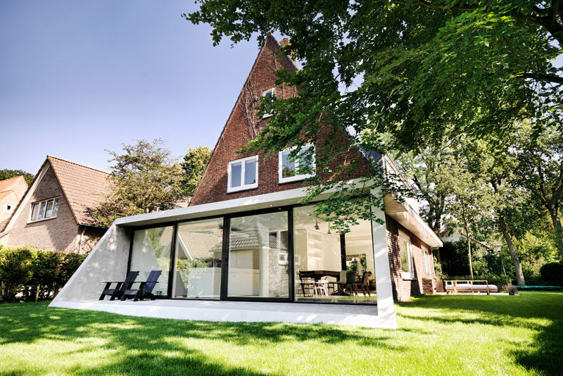 Architecture Ideas - This brick house received a new angled addition, that enlarged it with an open floor plan, added a view to the garden, and continues the slope of the original roof. #ModernArchitecture #HouseAddition #GlassWall