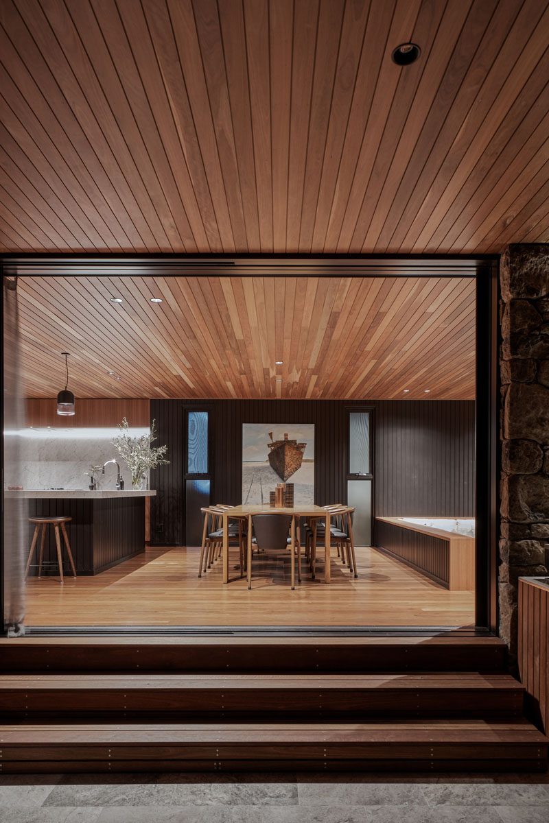 Separating the kitchen and the living room of this modern house, is the dining area. The wood ceiling seamlessly flows from the interior to the exterior spaces. #ModernDiningRoom #DiningRoomIdeas #WoodCeiling