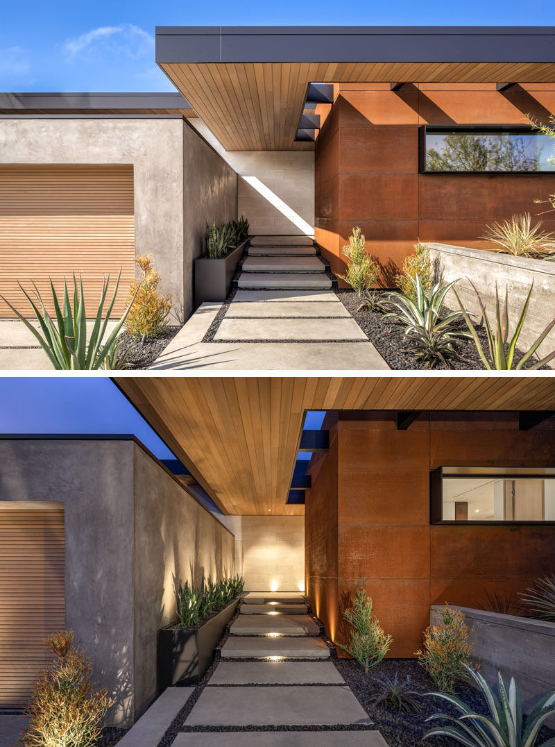 The facade of this modern house features a weathered steel accent, and plants that line the walkways. 