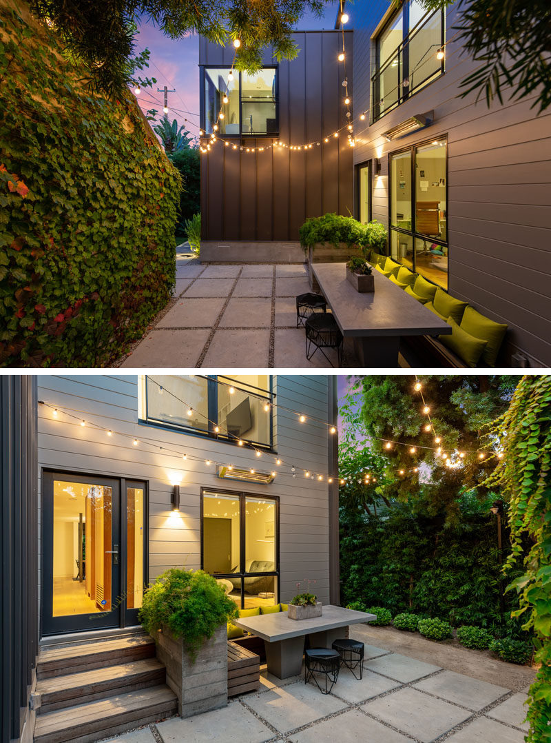 At the side of this modern house, there's a patio with decorative outdoor lighting that creates a welcoming atmosphere for the outdoor dining table with bench seating. #OutdoorEntertaining #OutdoorSpace #OutdoorLighting #OutdoorDining