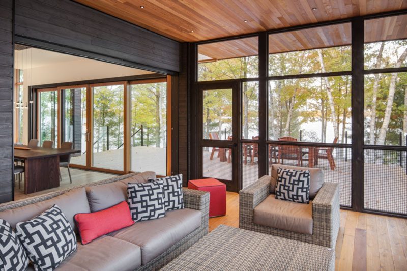 This modern lakeside house has a screened porch, and a large deck for outdoor entertaining. #ScreenedPorch #Deck #ModernLakesideHouse #ModernHouse #WoodCeiling