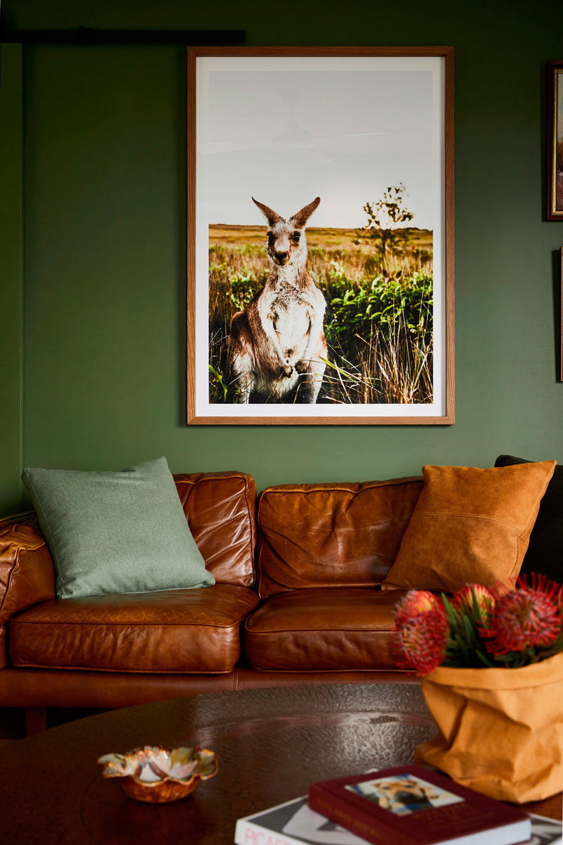 A deep green covers the walls in this modern living room and helps to connect the interior with the landscape. #LivingRoomIdeas #ModernLivingRoom