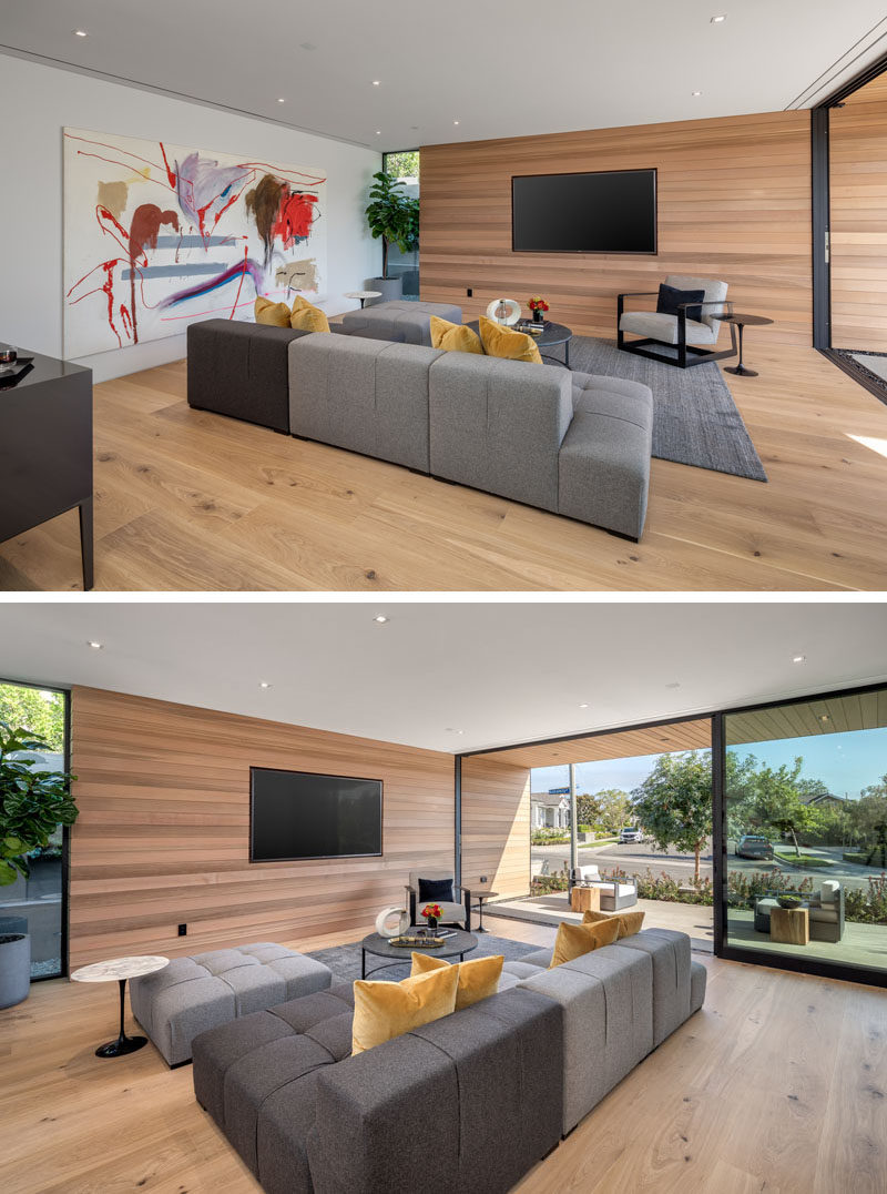 This modern living room has a television recessed into the wood wall, that also continues to the exterior of the house. 