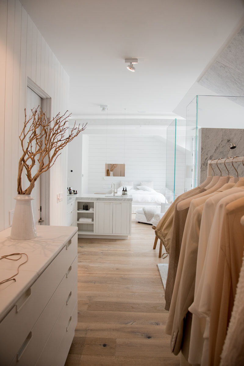 Bedroom Ideas - This master bedroom suite includes a sleeping area, an open bathroom, and a large walk-in closet. It uses light colors, glass, and natural light to keep it bright yet also relaxing. #MasterSuiteIdeas #MasterIdeas #ModernBedroom #BedroomIdeas #ModernBathroom #ModernWalkInCloset #ModernCloset