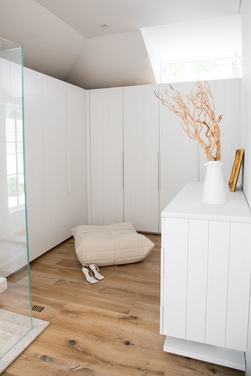 Closet Ideas - This modern master bedroom suite includes a walk-in closet, that features white panel cabinetry wardrobe doors, while a clerestory window adds natural light to the space. #WalkInCloset #WalkInWardrobe #MasterSuite #BedroomIdeas