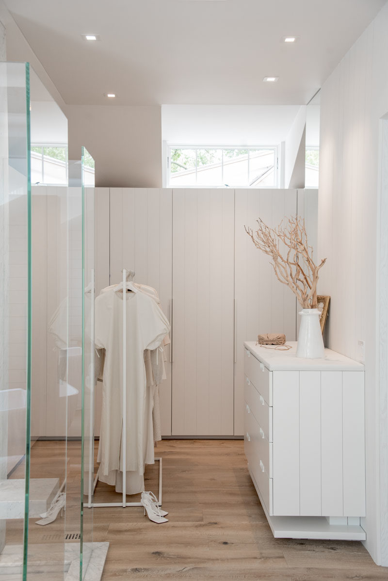 Closet Ideas - This modern master bedroom suite includes a walk-in closet, that features white panel cabinetry wardrobe doors, while a clerestory window adds natural light to the space. #WalkInCloset #WalkInWardrobe #MasterSuite #BedroomIdeas