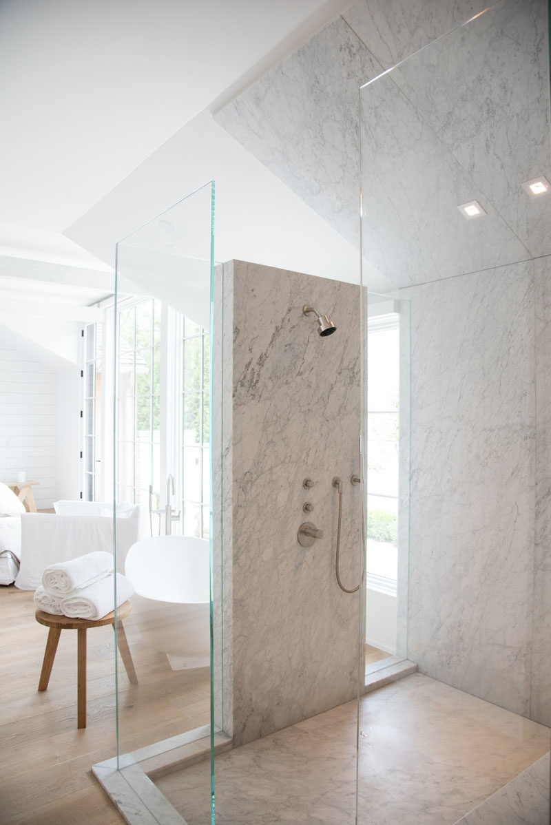 Bathroom Ideas - This modern bathroom that's open to the bedroom, features walls of glass and stone. #MasterSuite #ShowerIdeas #BathroomIdeas