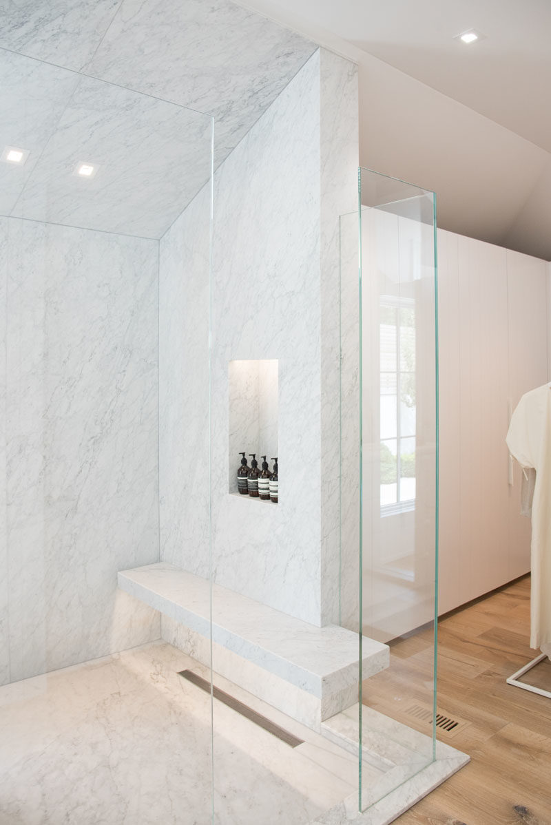 Bathroom Ideas - This modern glass enclosed shower features a built-in bench and shelf, both of which have hidden lighting to highlight the design details. #BathroomIdeas #ShowerIdeas #MasterBathroom