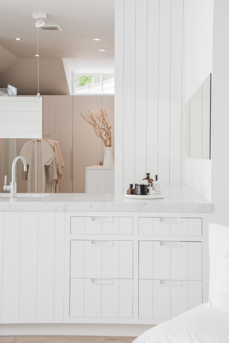 Bathroom Vanity Ideas - This modern master suite with an open bathroom and walk-in closet, has a custom-designed bathroom vanity with drawers that match the white panel cabinetry used throughout the space. #ModernBathroom #BathroomVanityIdeas #MasterSuite