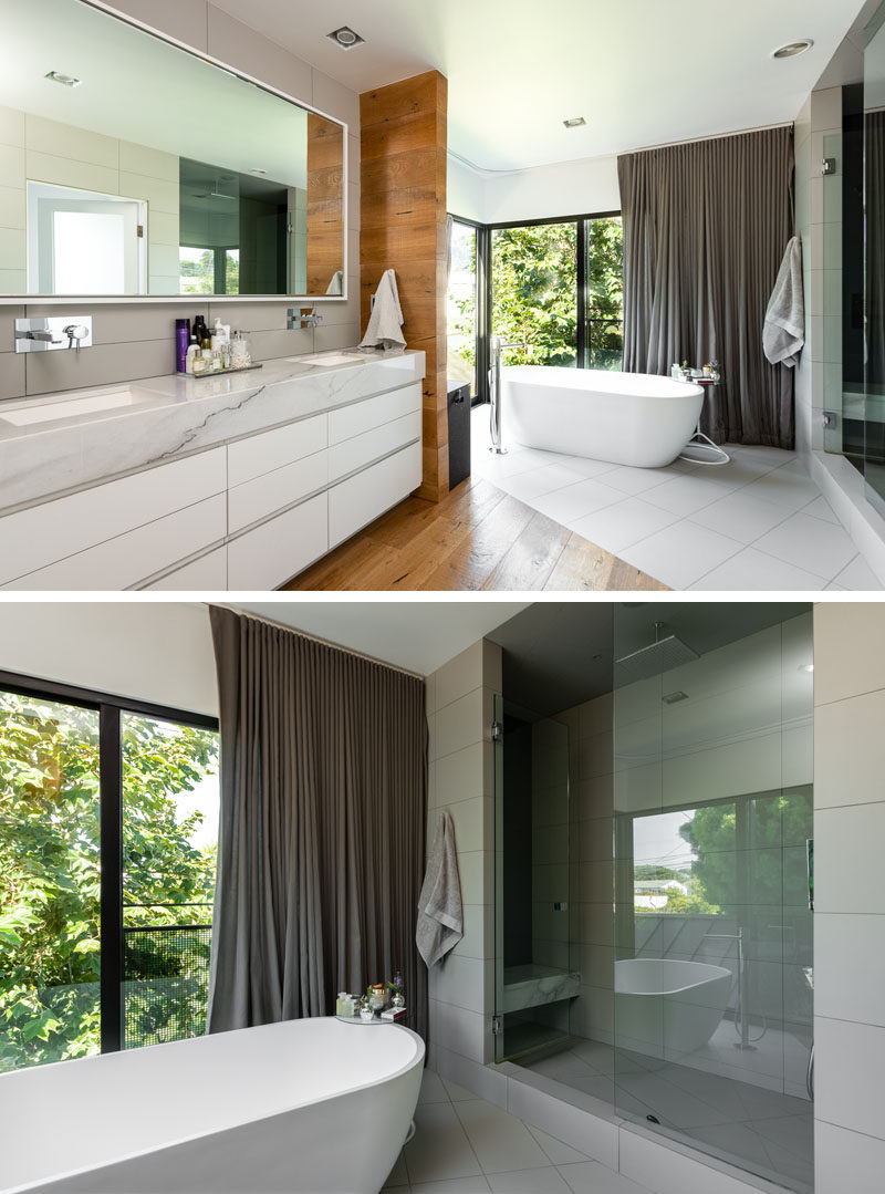 In this modern master bathroom, Calcutta marble has been used for the vanity and shower, while a free-standing soaking tub sits beside the windows. #MasterBathroom #BathroomDesign #BathroomVanity #FreestandingBathtub