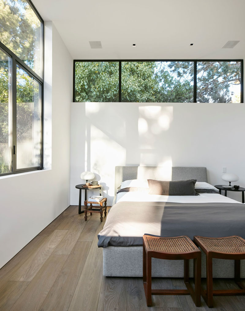 This modern master bedroom has a row of windows above the bed, with a second set of windows adding to the amount of the natural light the room receives. #ModernBedroom #BedroomDesign