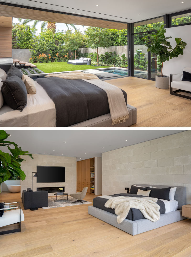 A modern master suite with retractable glass walls, custom European white oak flooring, limestone walls, and a sitting area with a fireplace and recessed television.