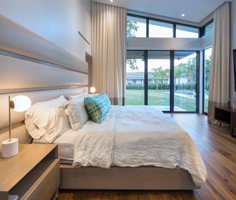 In this modern master bedroom, sliding glass doors open to the backyard, while a custom bed design incorporates bedside tables and a leather headboard. #MasterBedroomIdeas #ModernBedroom #BedroomDesign