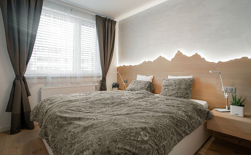 headboard Ideas - Using a mountain range as inspiration, this custom wood headboard with hidden lighting showcases the outline of the mountains and creates a soft glow for the bedroom. #HeadboardIdeas #ModernHeadboard #BedroomIdeas #BacklitHeadboard #ModernBedroom
