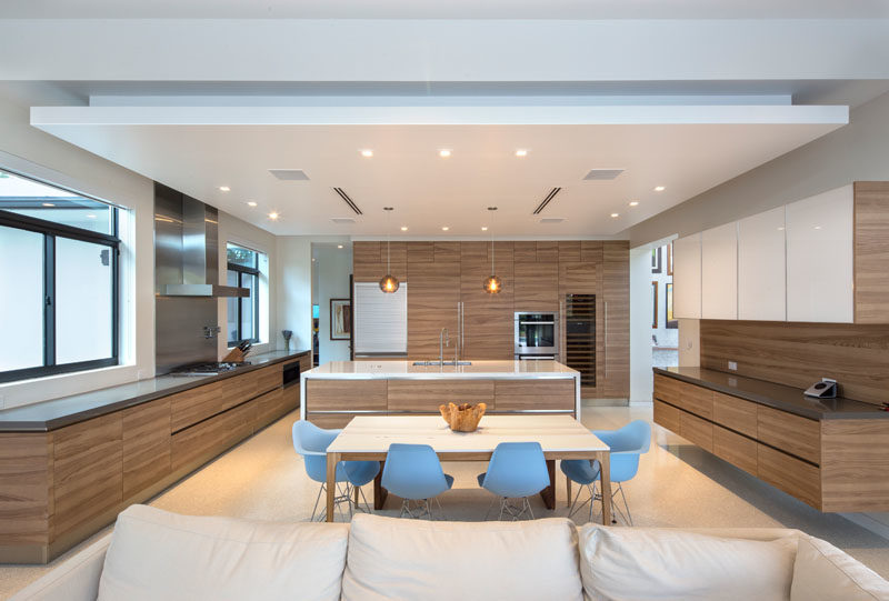 This large modern kitchen with wood cabinets shares the space with the dining area. #KitchenDesign #WoodKitchen