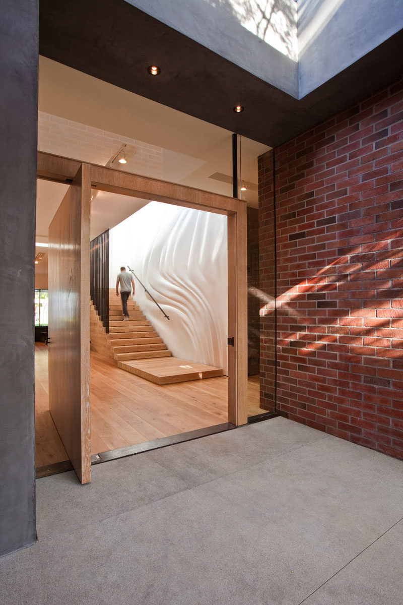 Stair Ideas - This modern house has a custom designed rough-sawn lumber staircase with a rippling and custom-molded wall that gives the illusion of a fabric curtain blowing in the wind. #ModernStairs #WoodStaircase #SculpturalWall