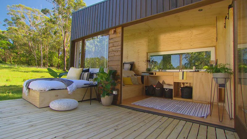 TIny House Ideas - This tiny house, which measures in at just 19 feet x 7 feet  (6m x 2.4m), has a simple modern design that covered in cypress pine cladding. Two siding doors were used to create the large picture window on the end of the house, while a large pivoting glass door opens the interior to the deck. #TinyHouseIdeas #ModernTinyHouse #TinyHouseDesign