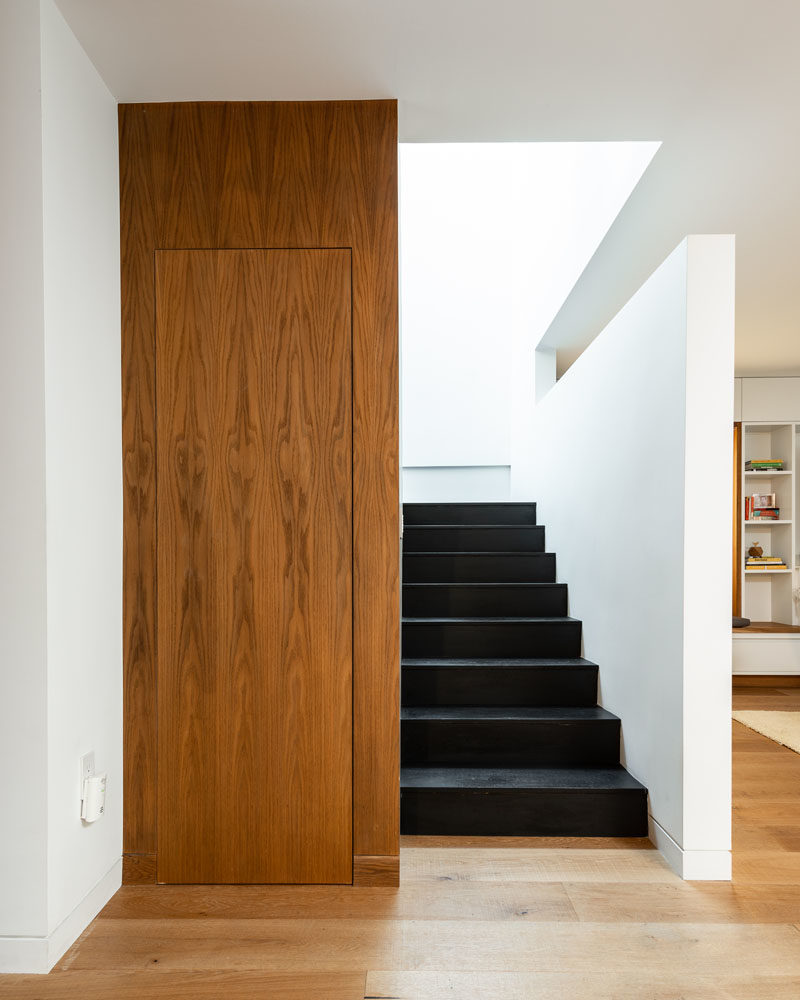 Stairs with dark treads located by the living room of this modern house, lead to the upper floor of the home. #ModernStairs #StairDesign