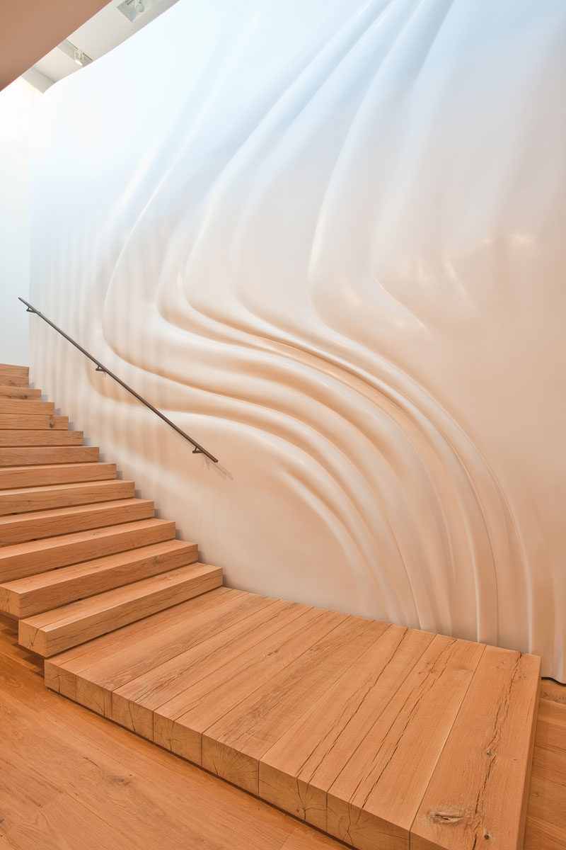 Stair Ideas - This modern house has a custom designed rough-sawn lumber staircase with a rippling and custom-molded wall that gives the illusion of a fabric curtain blowing in the wind. #ModernStairs #WoodStaircase #SculpturalWall