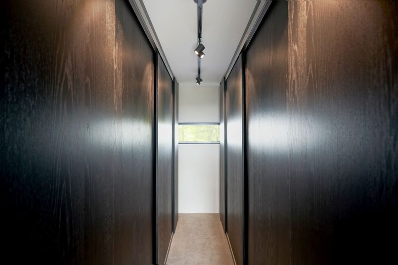 Dark wood walls have doors that slide open to reveal closets. #DarkWood #Closet