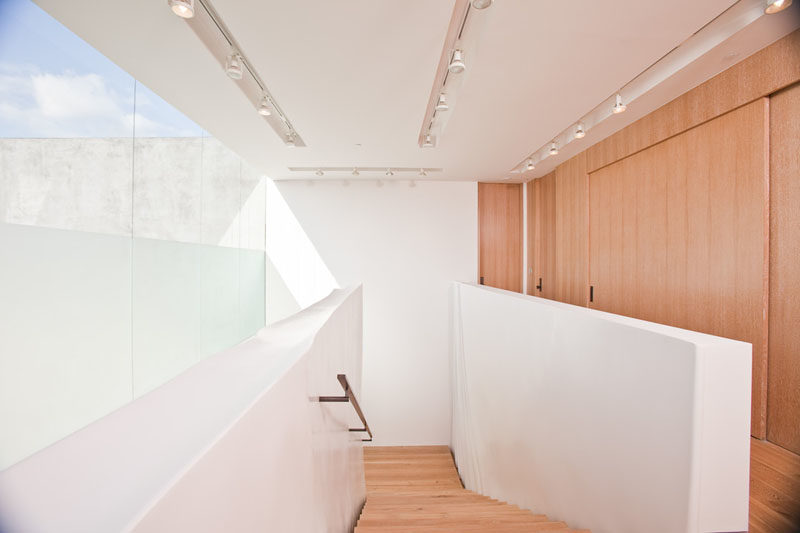 This modern house has a bright white and wood staircase, that matches its surroundings. #ModernHouse #ModernInterior