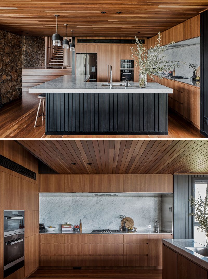 In this modern kitchen, a large L-shaped island with an overhanging countertop provides creates a place for the family to gather while cooking. #KitchenDesign #ModernKitchen #LShapedKitchenIsland #KitchenIslandDesign