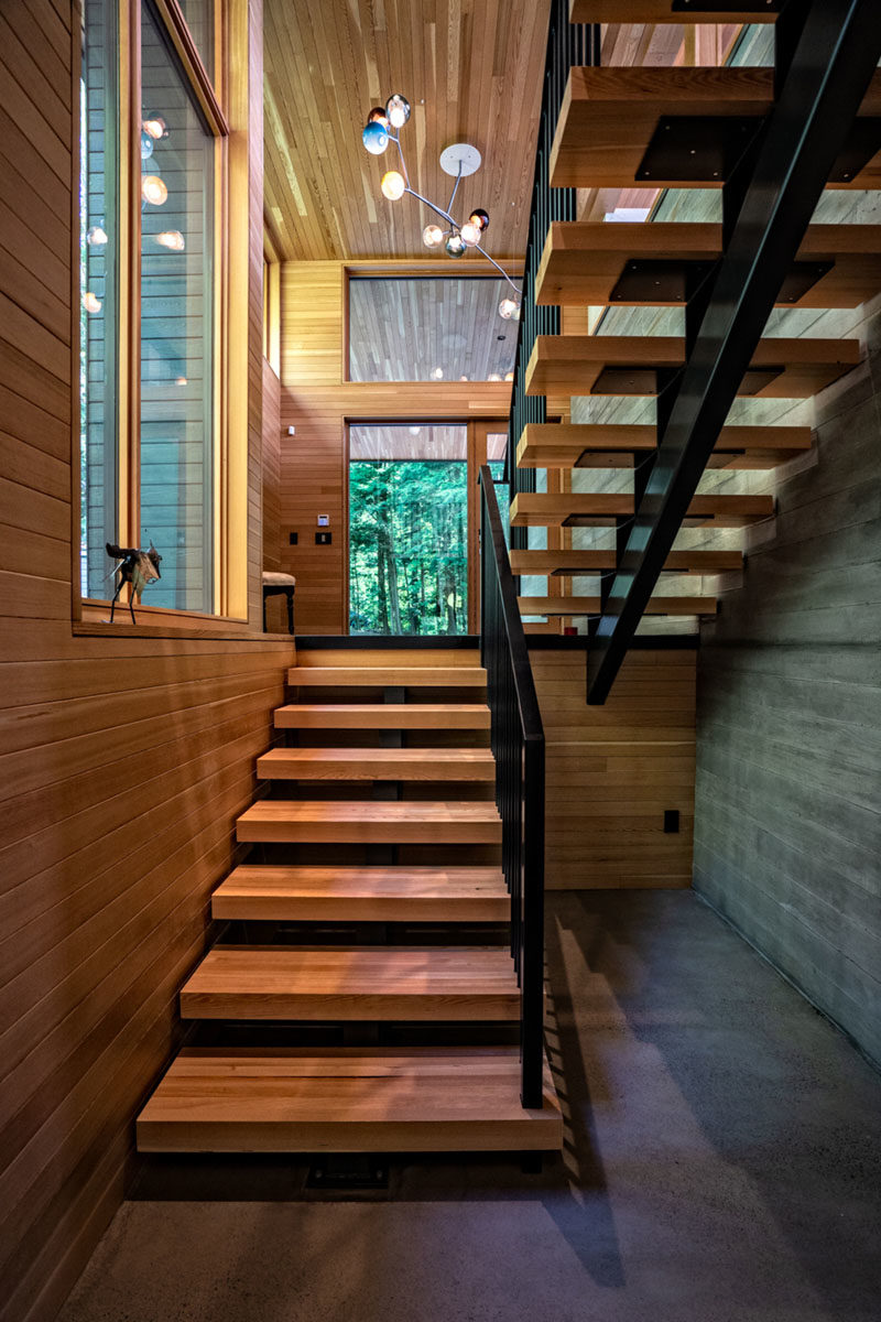 Stair Ideas - The stairs by the front door that run alongside a board-formed concrete wall, also connect to the bedrooms and bathrooms on the lower level of the house. #ModernStairs #WoodStairs #OpenStairs